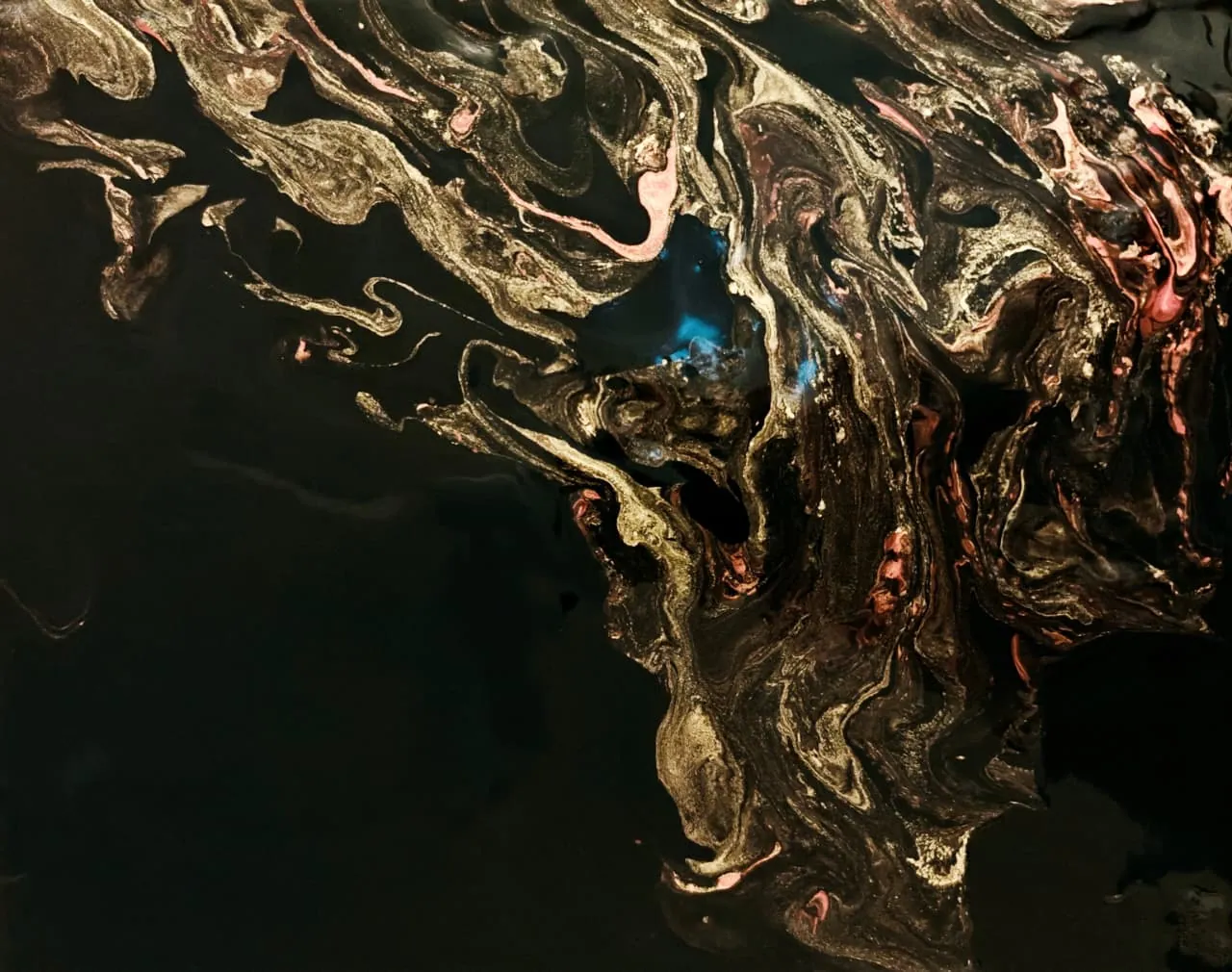 Gold, copper, and pink veins marbled across deep black with a small turquoise glow at the centre, like the fire caught in a black opal.