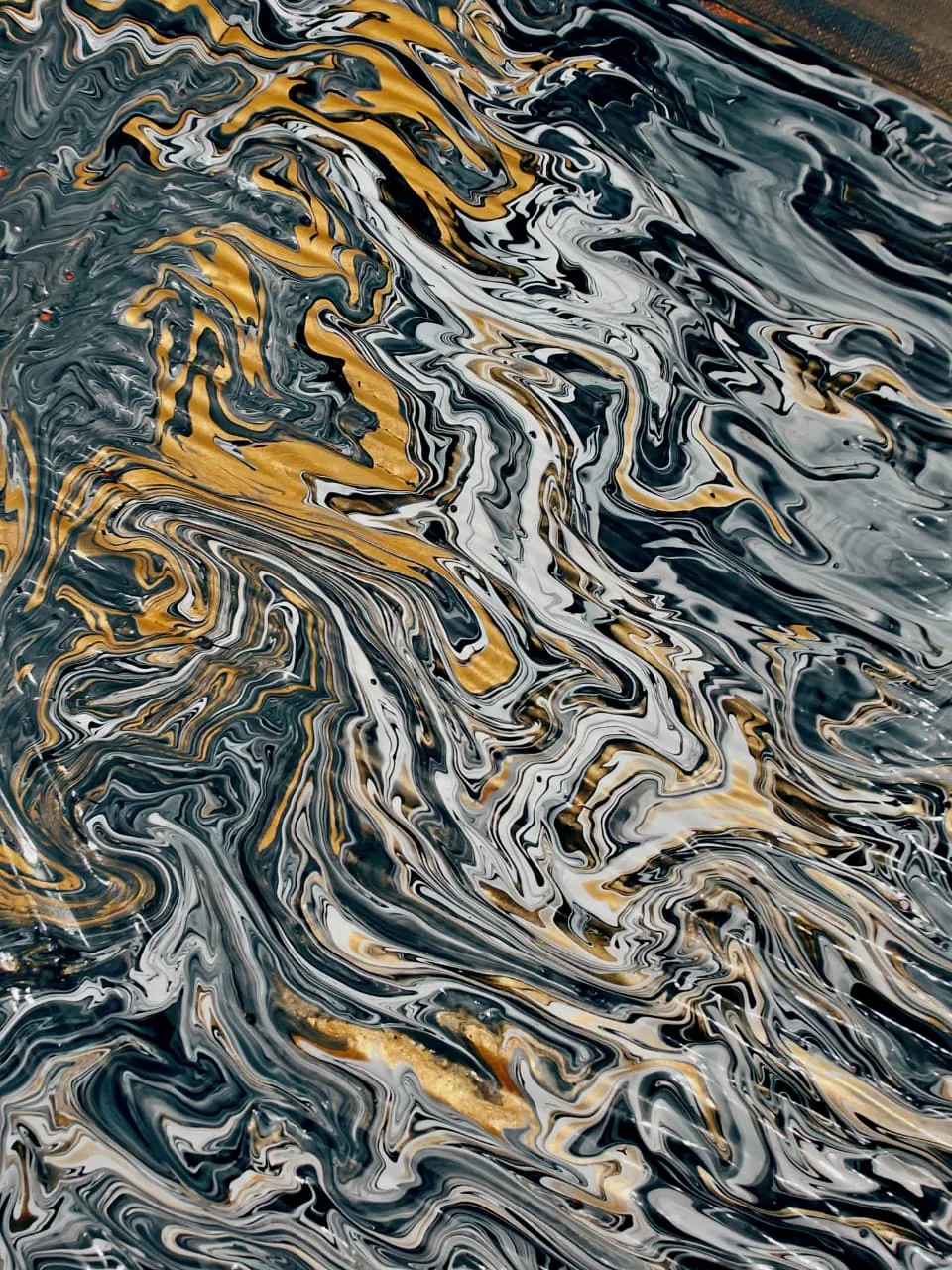 A poured painting seen close: fine marbled swirls of slate grey and white with streaks and pools of metallic gold threading through them from the upper left, like rutile needles caught in quartz.