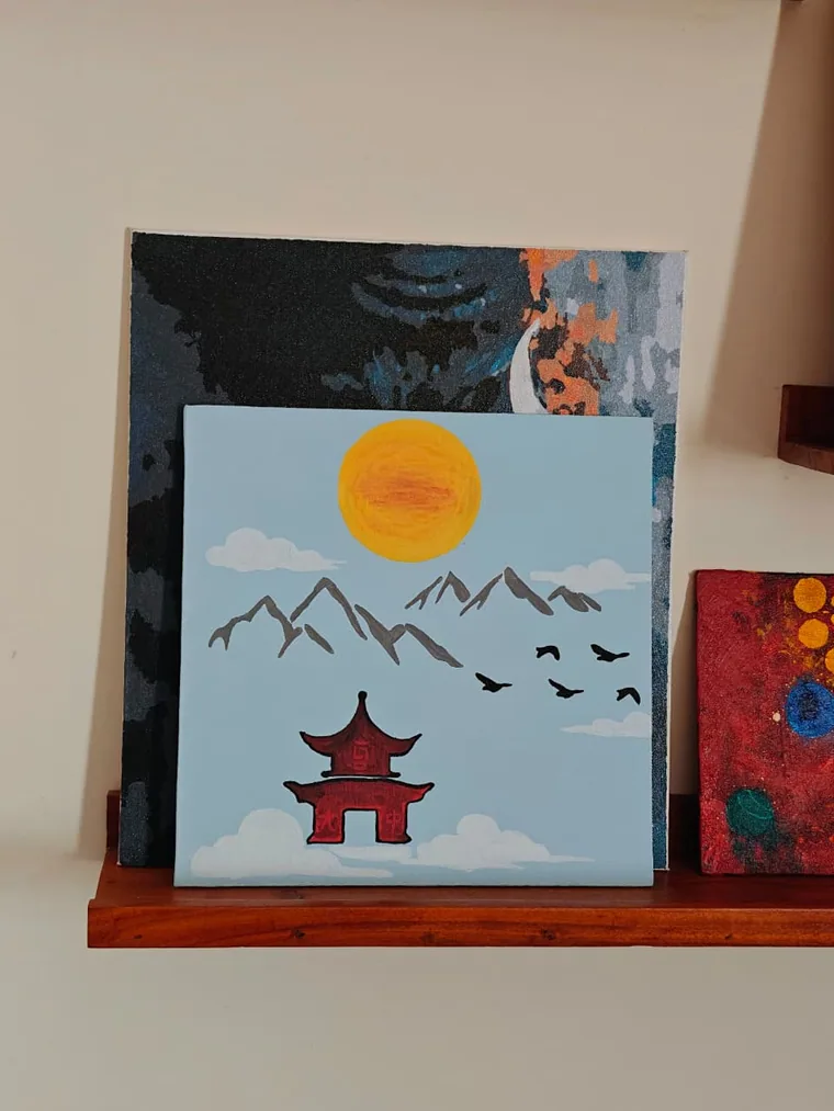 A flat-colour painting of a red pagoda temple resting on a bank of white cloud, with grey mountain peaks, a yellow sun and a skein of dark birds against a pale blue sky.